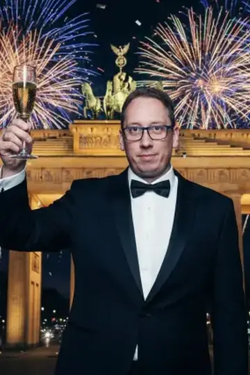 KI-Look Silvester: Silvester im Smoking mit Sektglas, hinter dir das Feuerwerk.