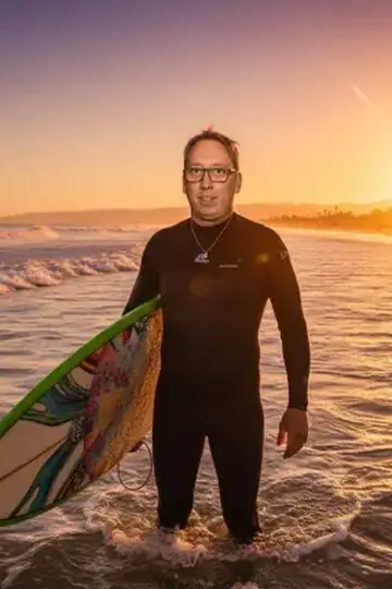 KI-Look Surfer Sunset: Im Neoprenanzug mit Surfbrett bei Sonnenuntergang.